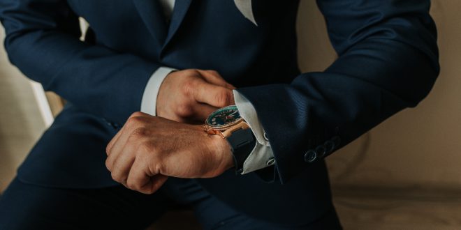 businessman in black costume wind clock (wristwatch) on hand