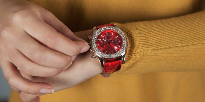 woman hand holding red watch on yellow background