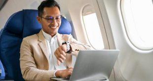 Successful and smart businessman sits at the window seat in business class, checking his watch for the arrival time, on the flight for his business trip.